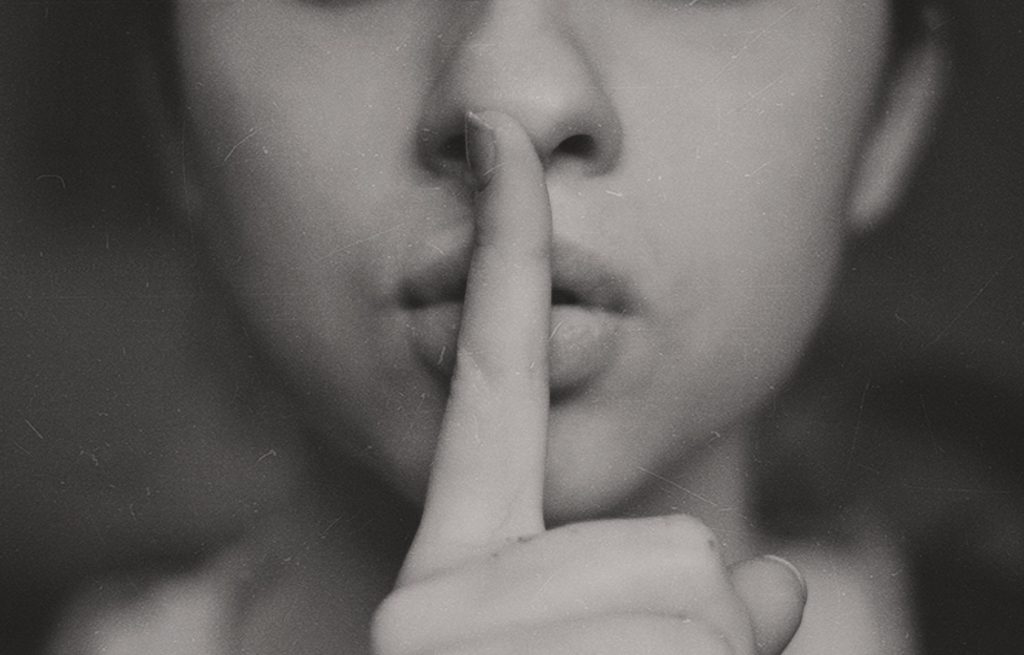 Image of a woman with her finger over her mouth for silence